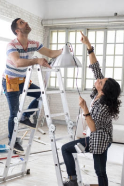 Couple installing a light on a ladder