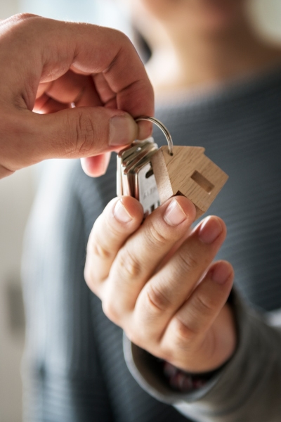 Hands passing set of keys with house shaped keychain