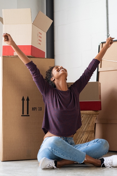Woman seated in front of boxes with look of joy and outstretched hands