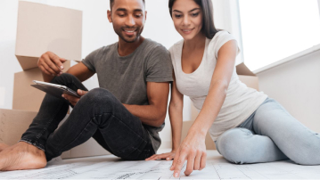 Couple sitting on floor looking at home plans