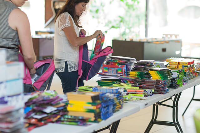 AFC employee donating to There with Care backpack drive