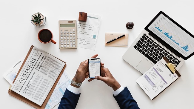 Man calculating finances on phone and calculator.