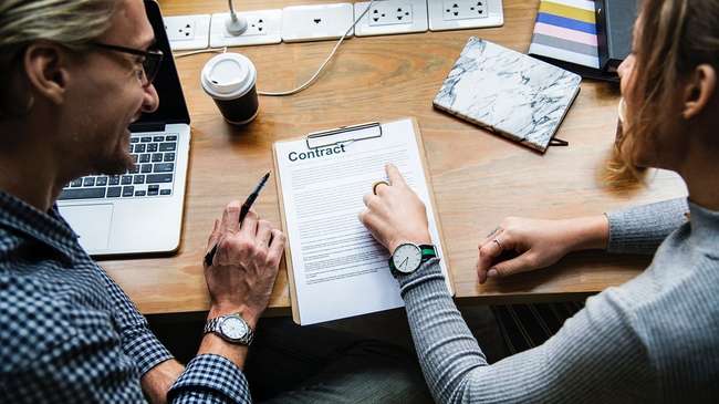 Woman in gray sweater signing contract