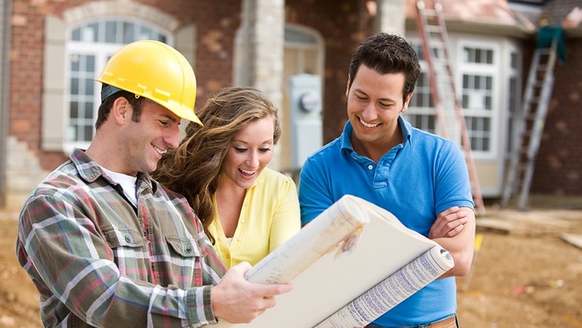 Happy couple reviewing home plans with builder