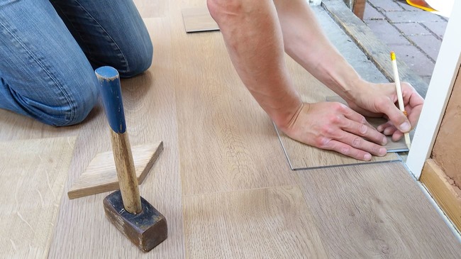 Carpenter taking floor measurements with pencil
