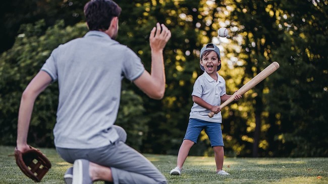 Father and son playing baseball on a sunny day