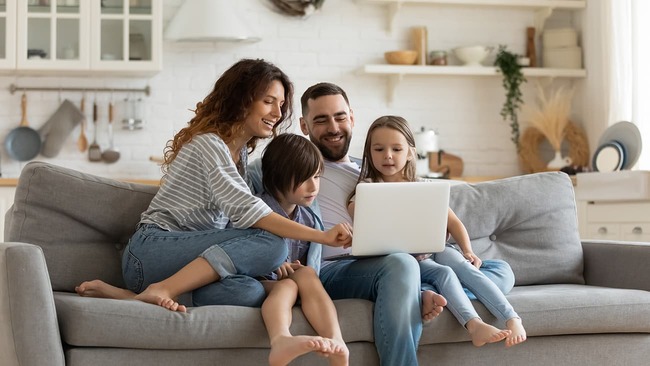 Happy family sitting on couch and looking at laptop
