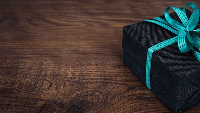 Black gift package with blue bow on wood table