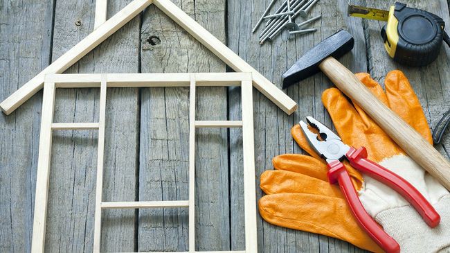 Frame of a house next to tools and gloves.