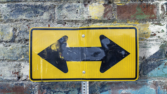 Yellow sign pointing directions for what's next