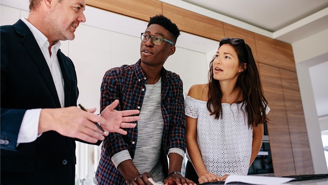 Couple talking with real estate agent inside new home