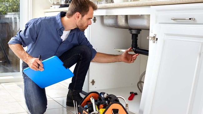 Plumber fixing kitchen sink