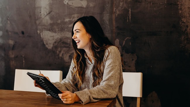 Woman laughing while sitting at table with tablet