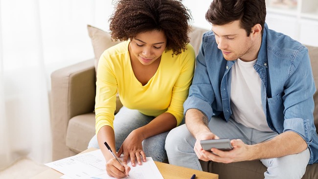 Couple making a budget while sitting on couch