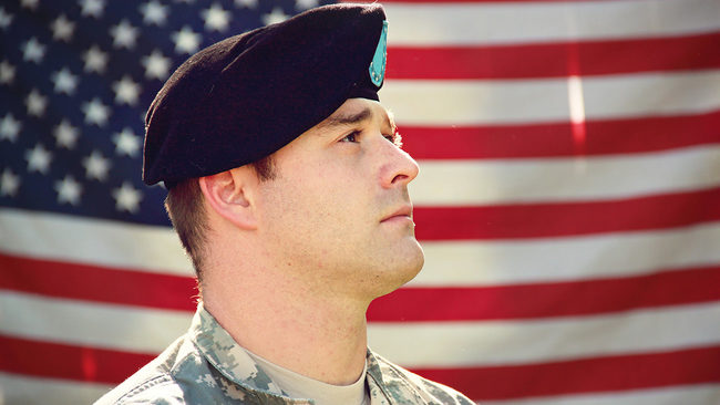 Military veteran standing near American flag