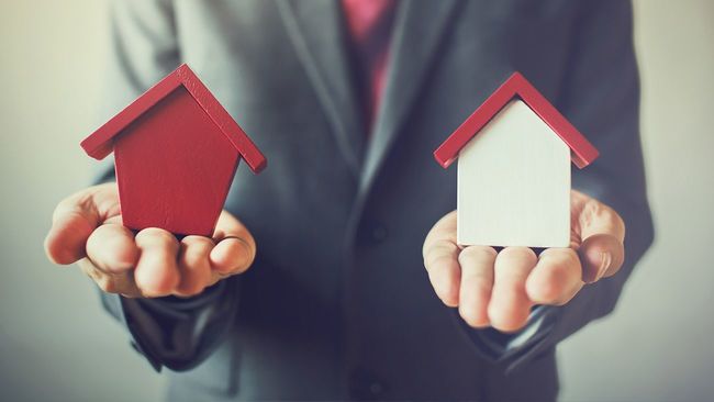 Man holding two toy homes