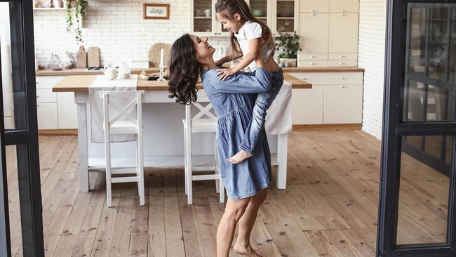 A mother and her child dancing in the kitchen
