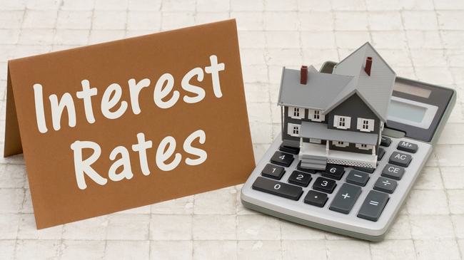 Interest rates sign next to small house and calculator