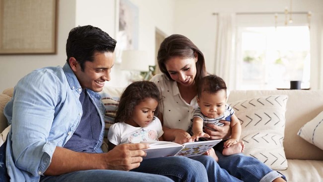 Young family reading a book in living room