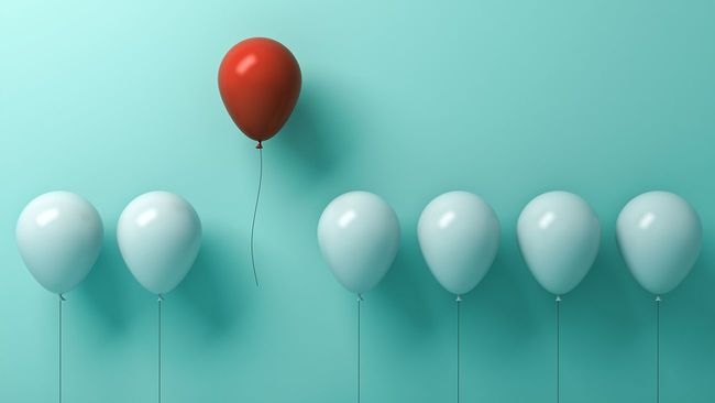 Red balloon floating above six white balloons
