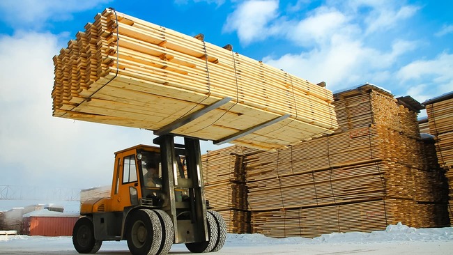 Machine lifting lumber in wood factory