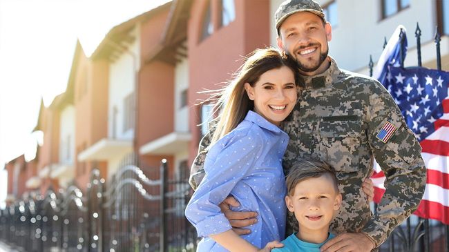 Veteran standing outside of home with family.