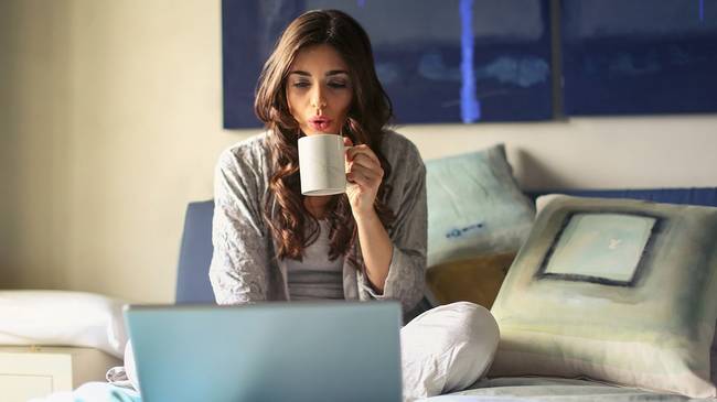 Woman drinking coffee at computer, researching mortgages