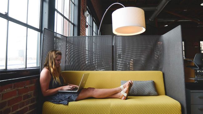 Woman in coworking space sitting on yellow couch