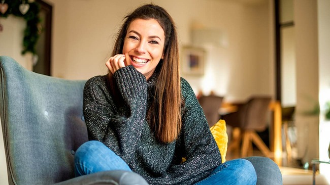 A woman smiling while sitting in her living room